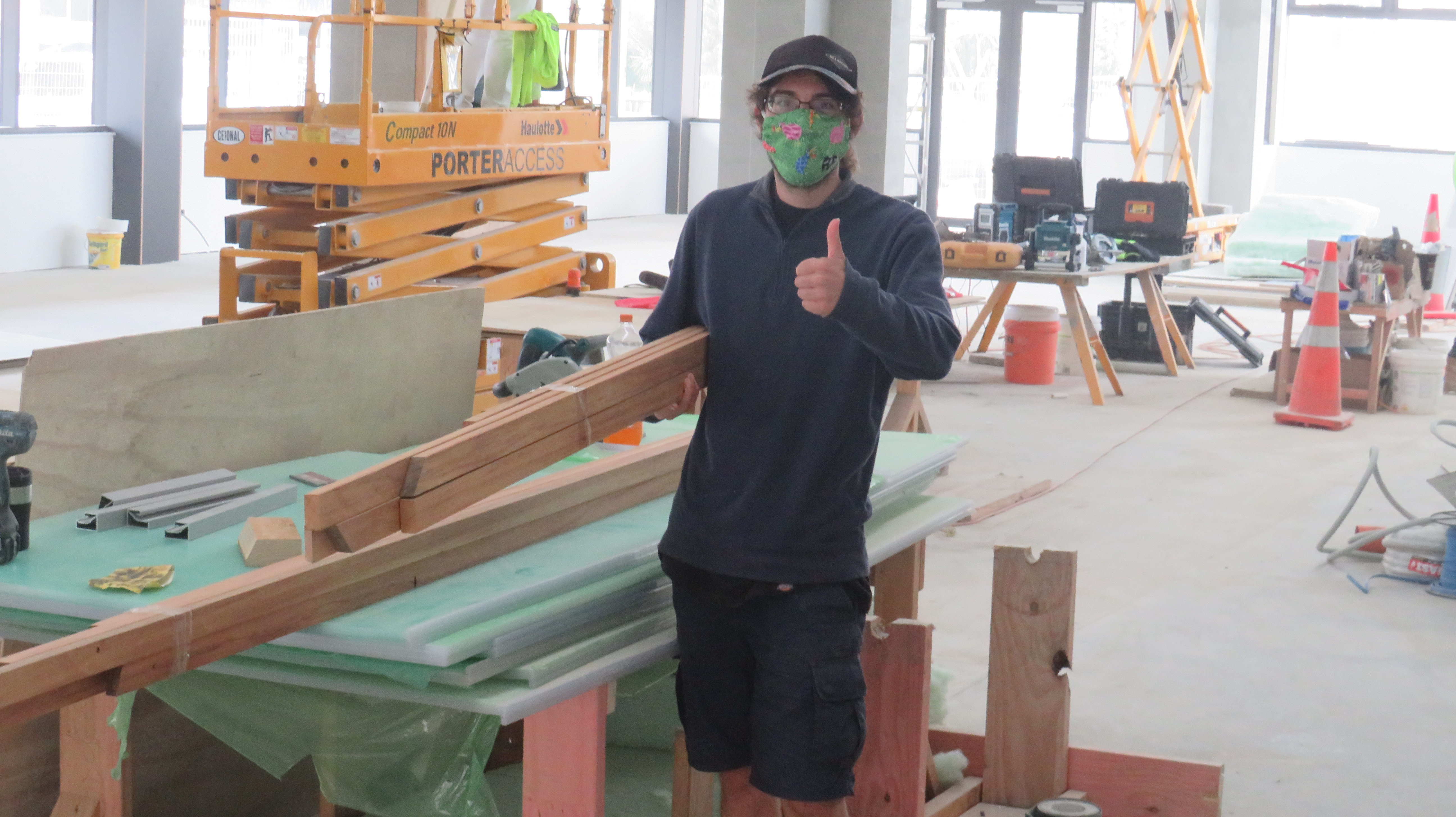 Image of Rueben Aikman carrying framing timber being used to frame the art that will go on the pou pou in the interior of Te Tāhuhu o Te Rangi.