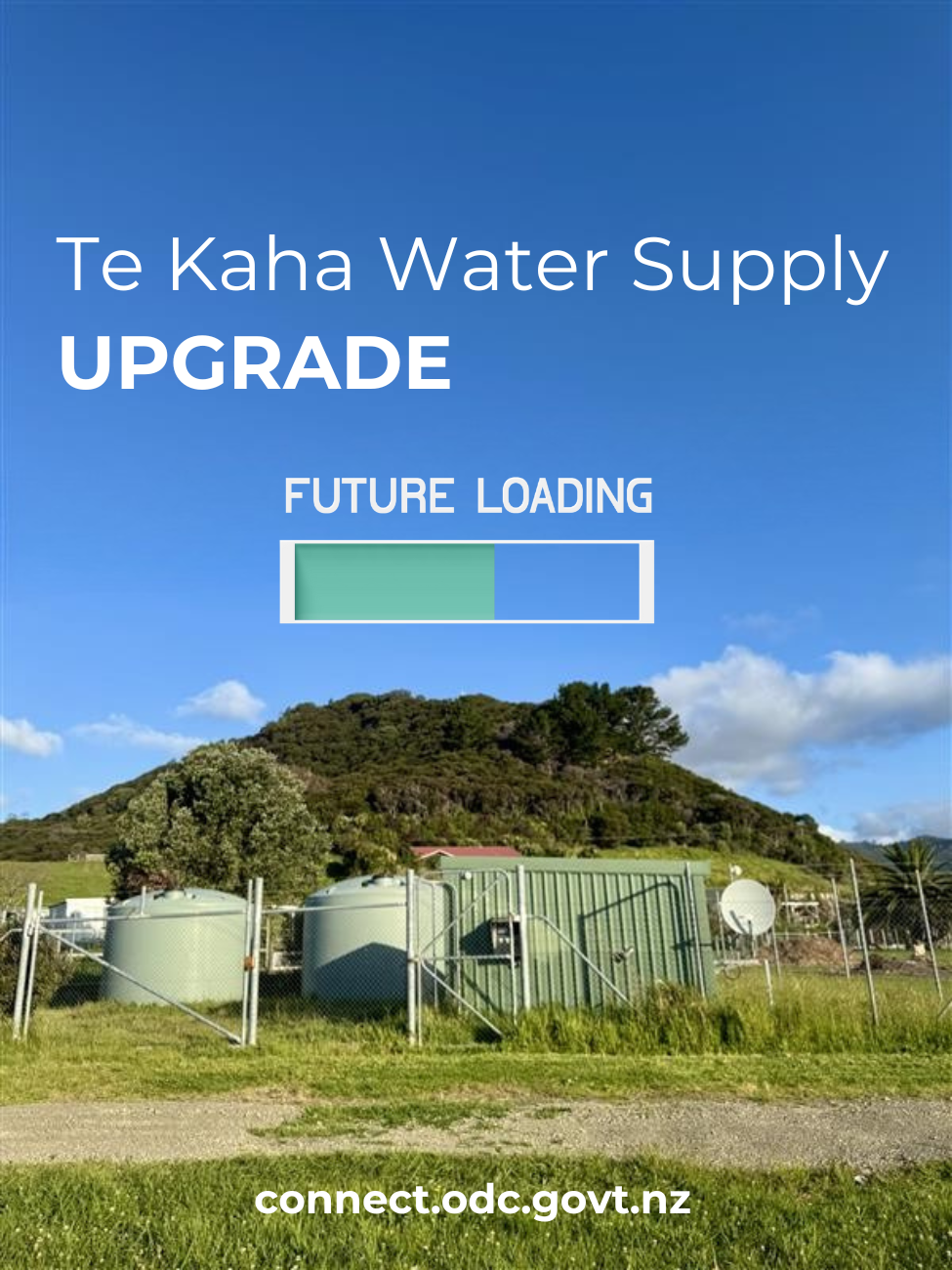 The large green tanks and security fences of Te Kaha water treatment plant are in front of a green hill with a blue sky and clouds behind. 